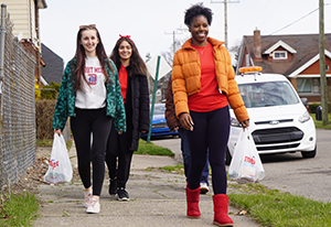 TENN students walk down a sidewalk carrying bags of food during a delivery day.