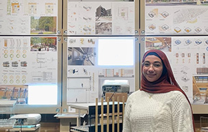 Zaynab Alhisnawi stands next to one of her design posters.
