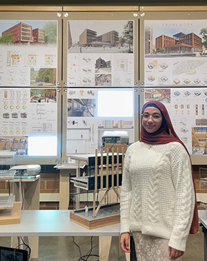 Zaynab Alhisnawi stands next to one of her design posters.