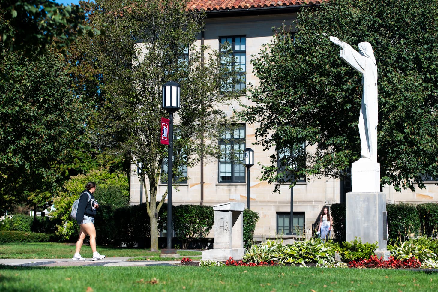 students walking near statue among fall foliage