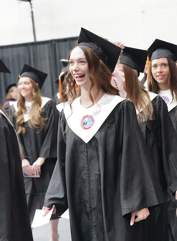 Graduates smile as they enter for commencement.