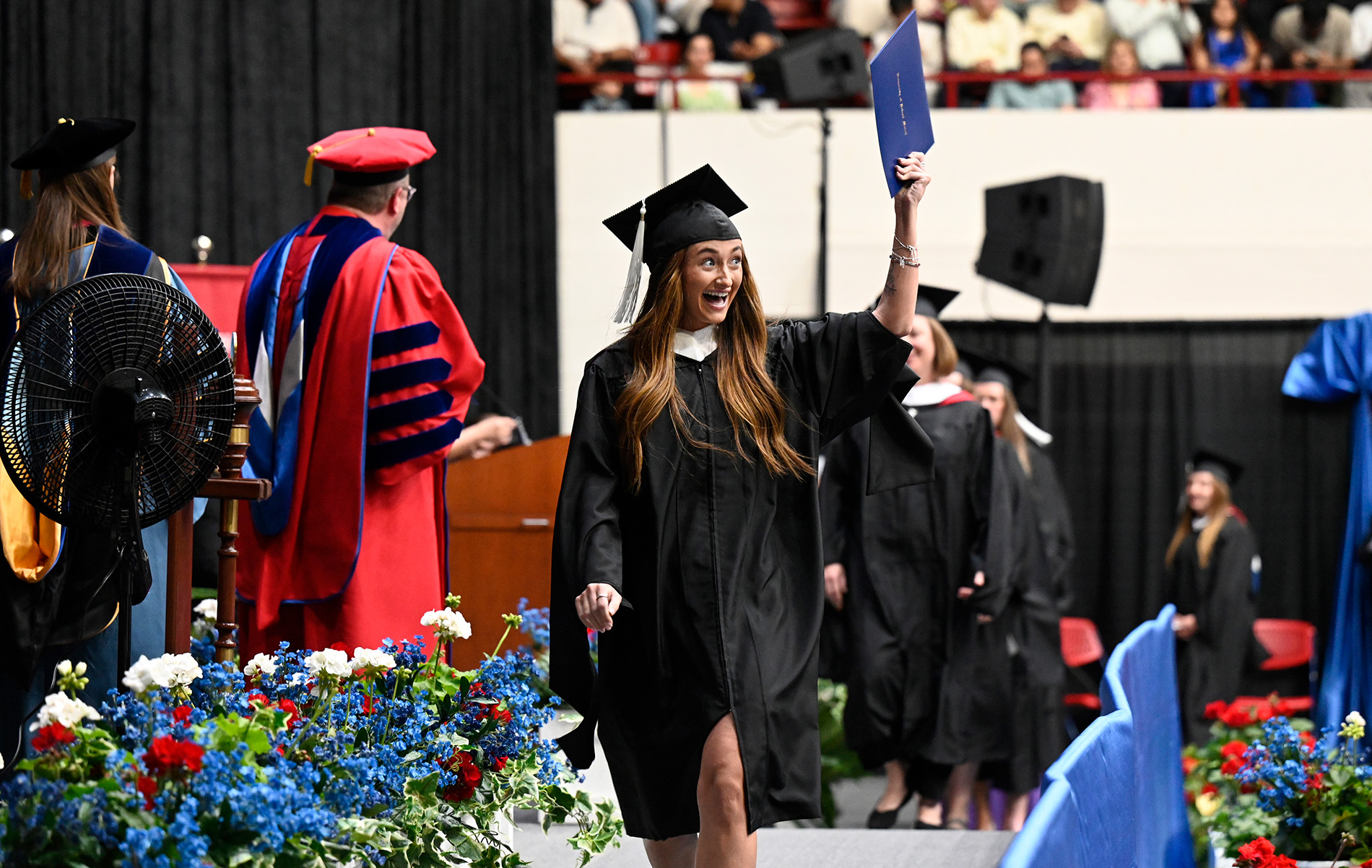 A student holds up her diploma as she walks across the Calihan Hall stage.