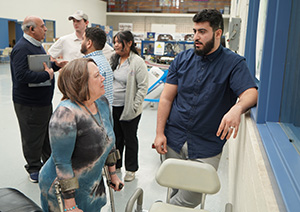 Nancy Flaharty stands next to the project her team designed for her as she talks to a student after the Faces on Design presentation.