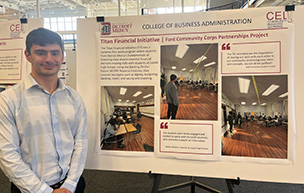 Mark Formosa stands next to a presentation poster entitled Titan Financial Initiative.