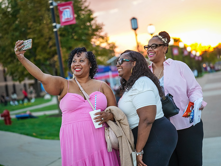A group of women take a selfie at Homecoming.