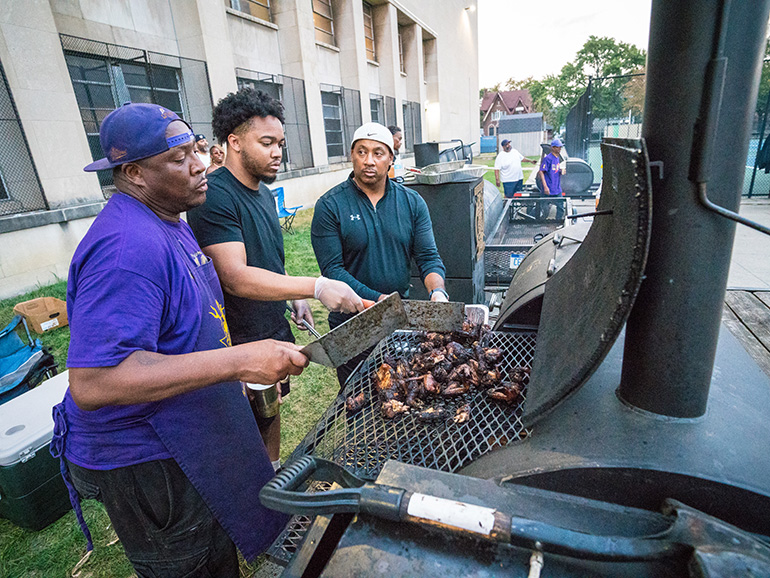 A group of men cook chicken wings during Homecoming.