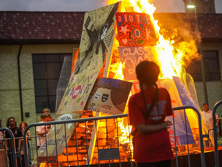 People watch the annual homecoming bonfire, which features signs made by student groups.