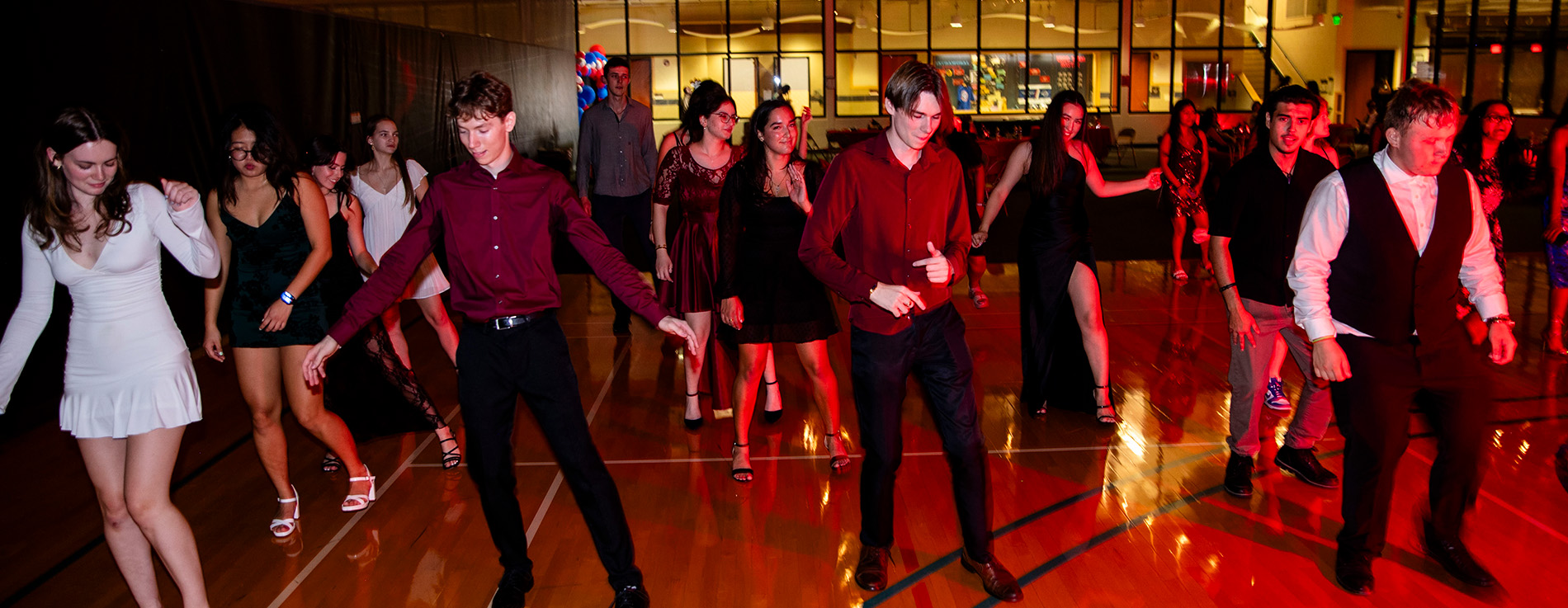 A large group of students have fun and dance at the homecoming dance.