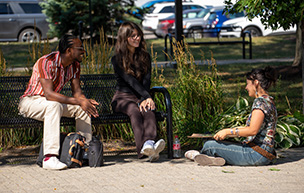 Three students sit by the fountain on the McNichols Campus.