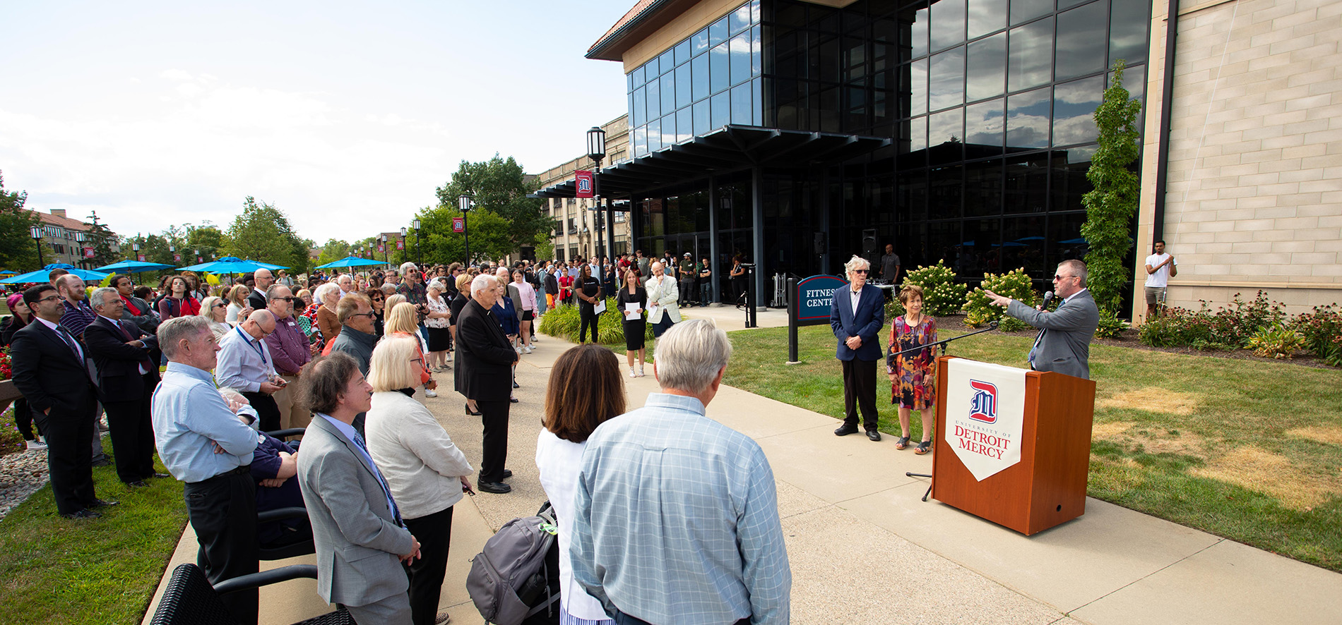 President Taylor speaks during the Whitty renaming ceremony, as a large crowd gathers around him and the Whittys.