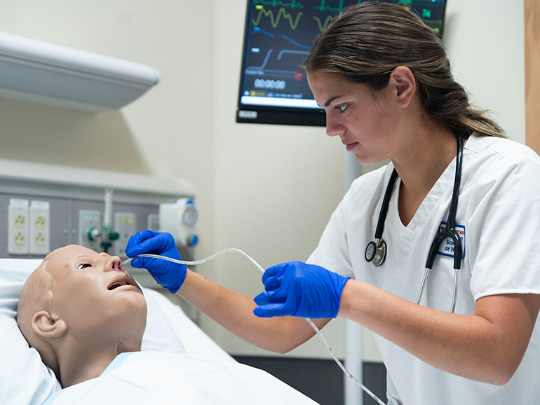 A Nursing student works on a manikin. 
