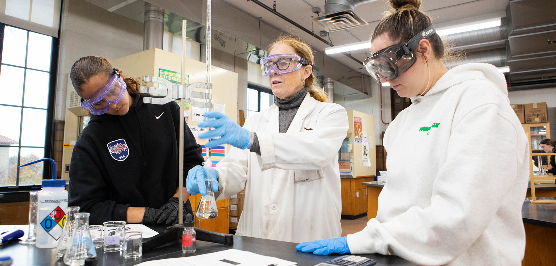 Students watch as their professor helps them in a Chemistry lab.
