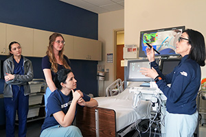 a nursing professor works with several nursing students in a simulation.