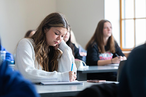 a student takes notes in a classroom.