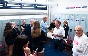 Several people stand in the new women's soccer locker room.