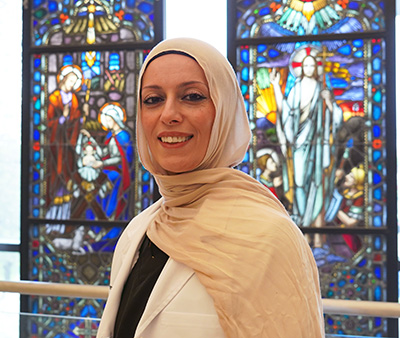 Shreen Marini stands near the Health Professions stained glass.