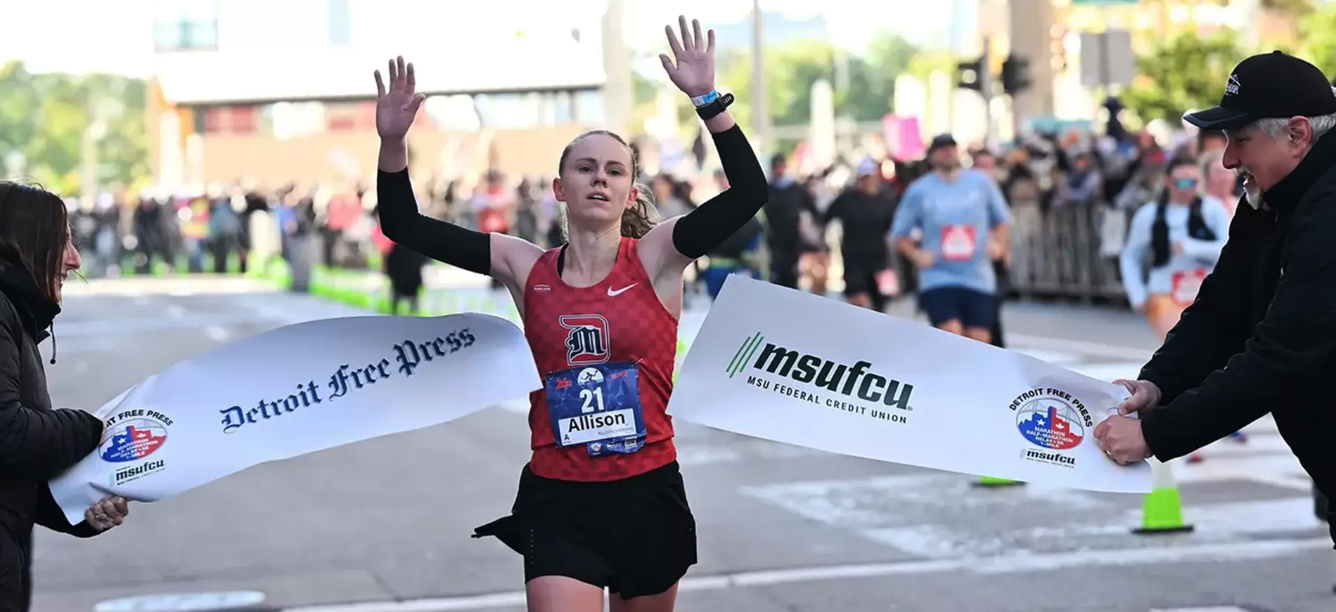 Allison Sherman '24 raises her arms in celebration as she crosses the finish line to win the Detroit Free Press Marathon.