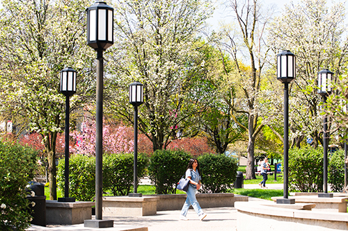 A student walks on the McNichols Campus during springtime.