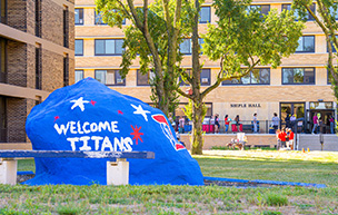 The rock is painted with the message "welcome Titans" while in the background, students are seen moving into Shiple Hall.