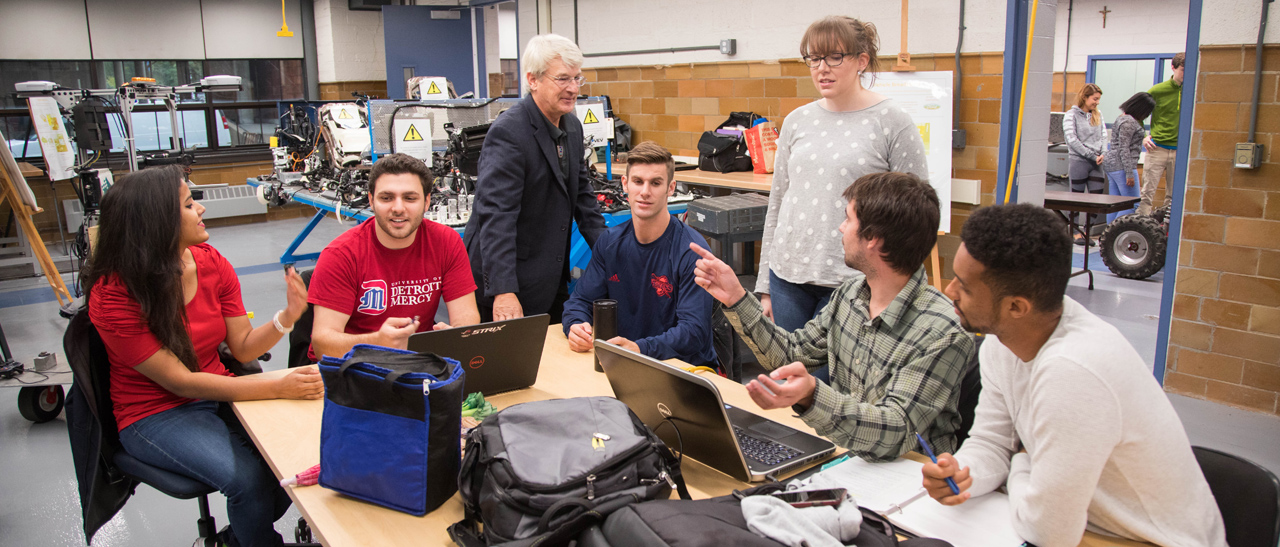 Students talk with a professor.
