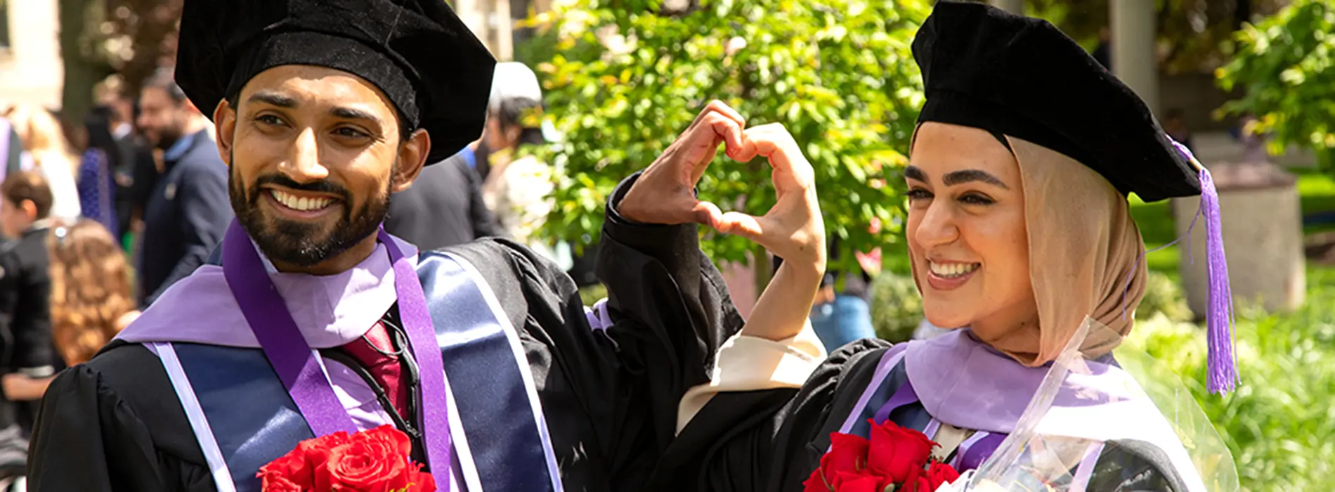 new graduates making a heart with their hands