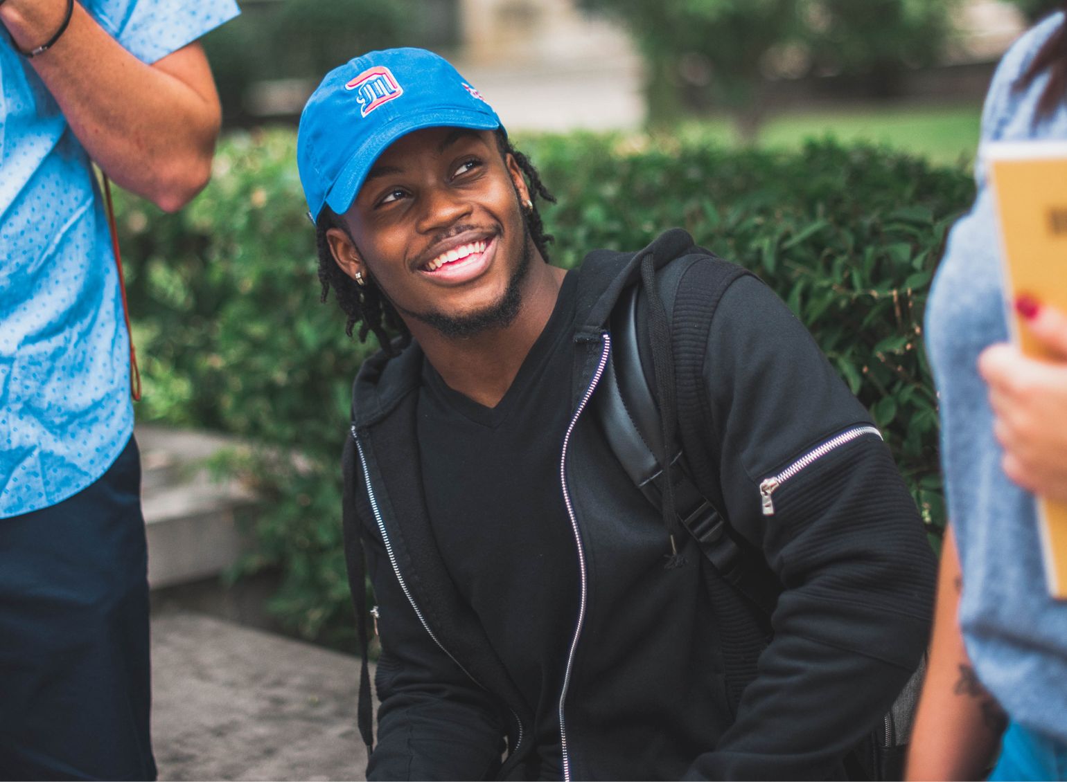 A student in a Detroit Mercy hat smiles.