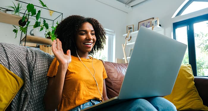 student waving happily at her computer