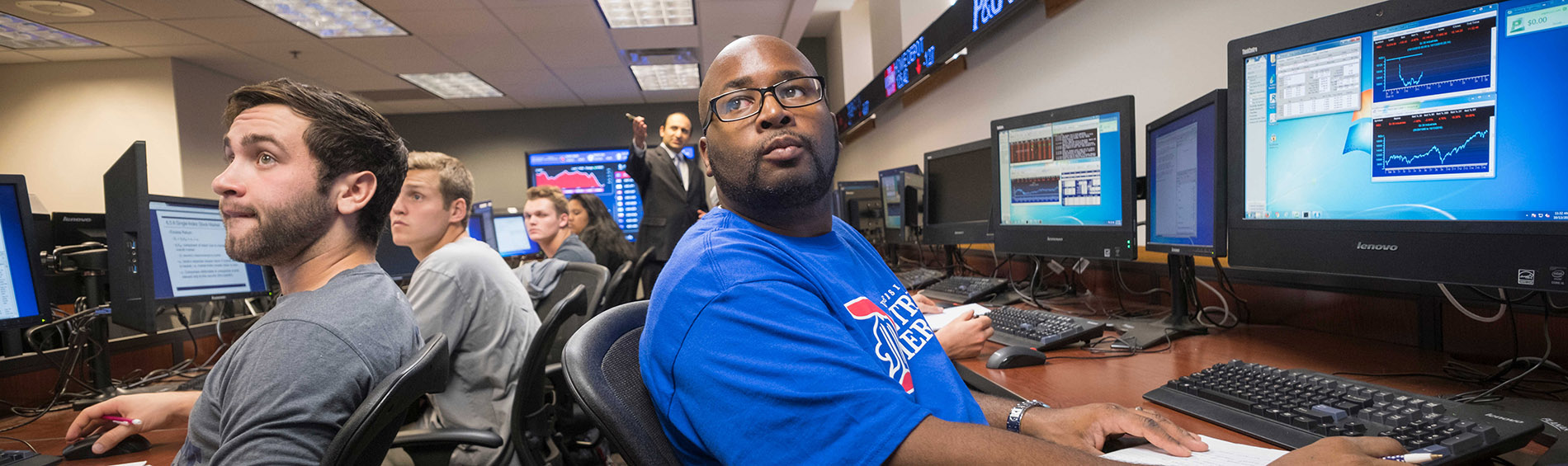 students in the markets lab with stock ticker in the background