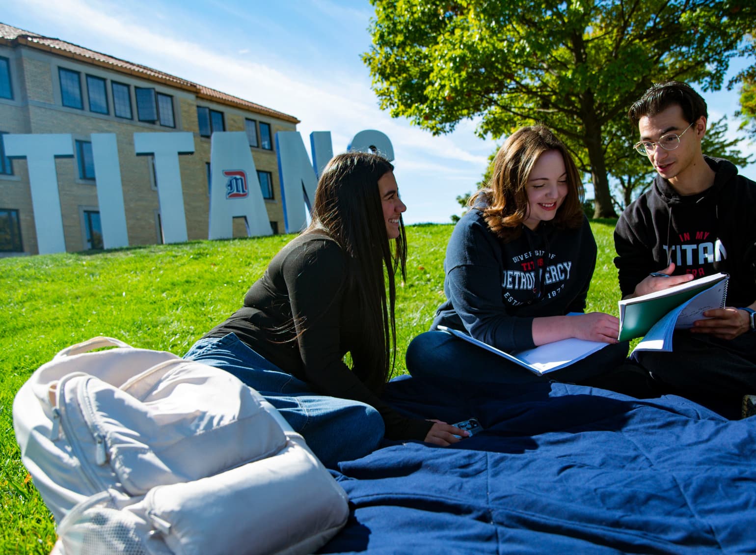 Students sit on a blanket in front of the Titans sign.