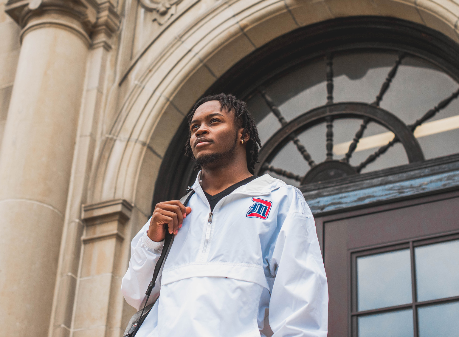 A male student stands outside an academic building.