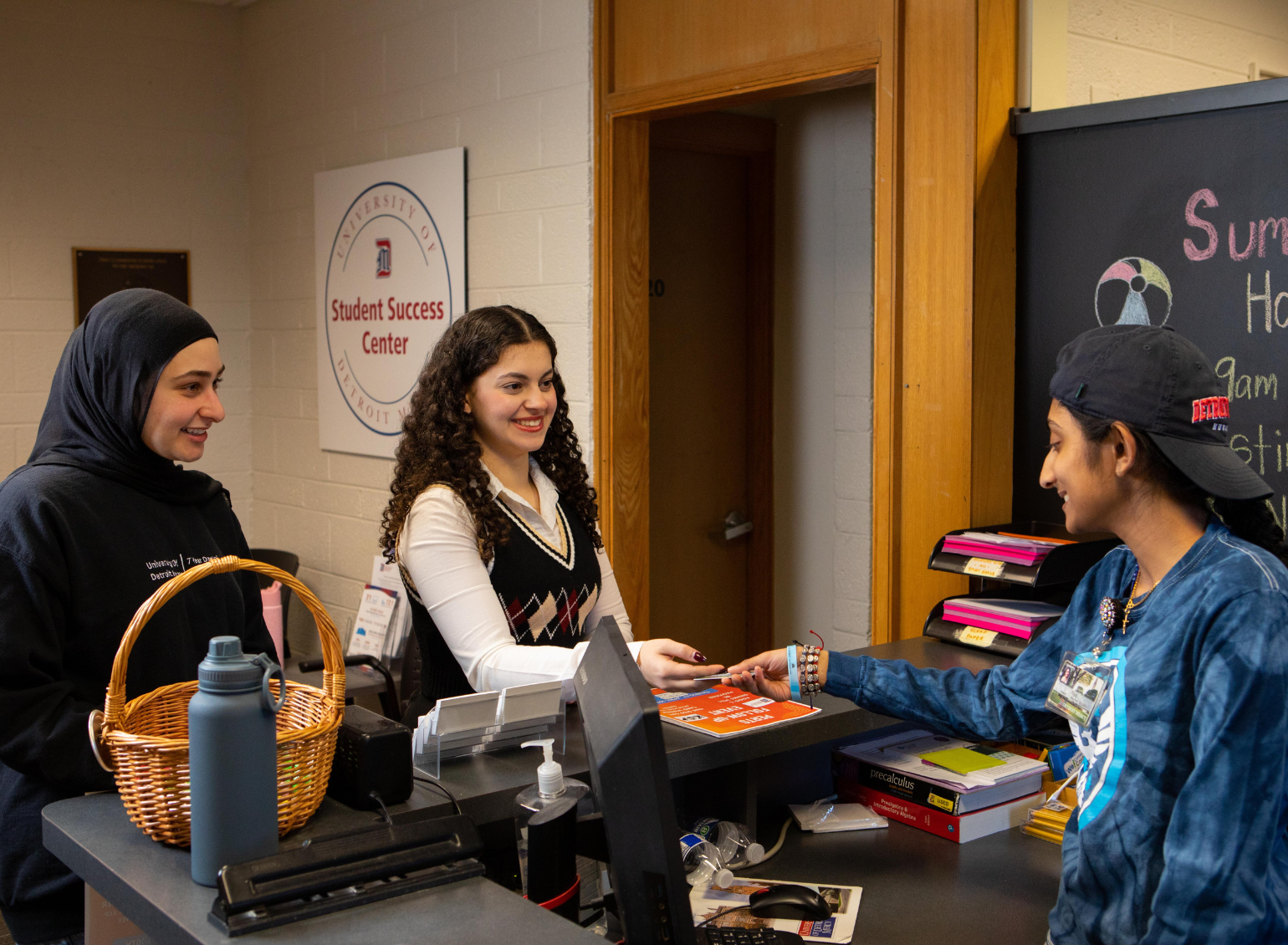A student hands her ID card to the receptionist in the Student Success Center.
