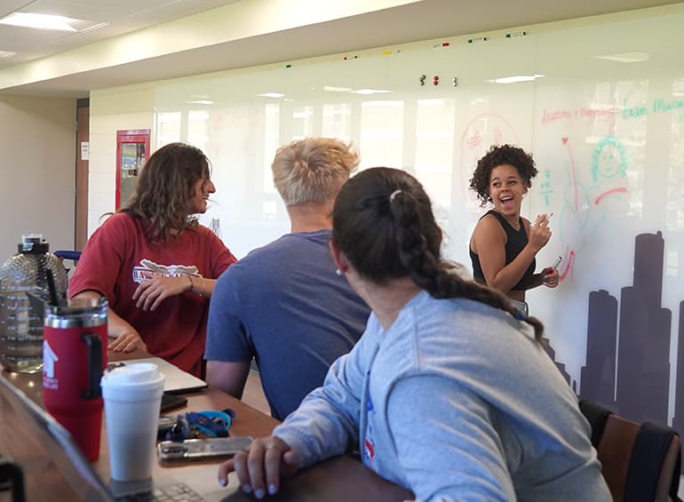 students using the city-scape whiteboard in shiple lobby