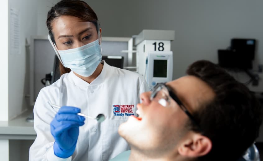 Female dental student looking in the mouth of male patient