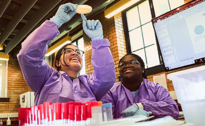 two female biology students looking at a petrie dish