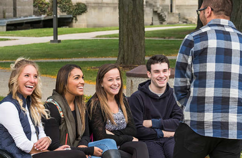 Students laughing on a bench