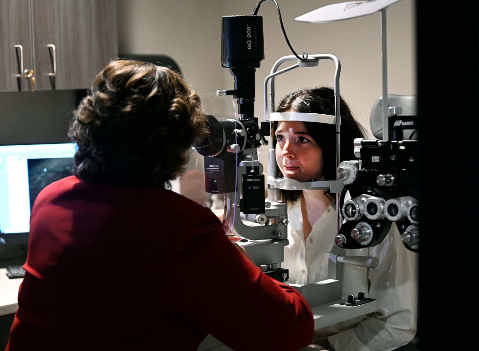An optometry student examines a patient's eyes.