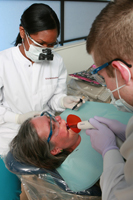 A patient undergoes examination by two Detroit Mercy Dental professionals.
