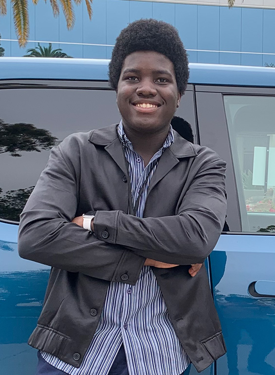 Agholor stands next to a blue Rivian car.