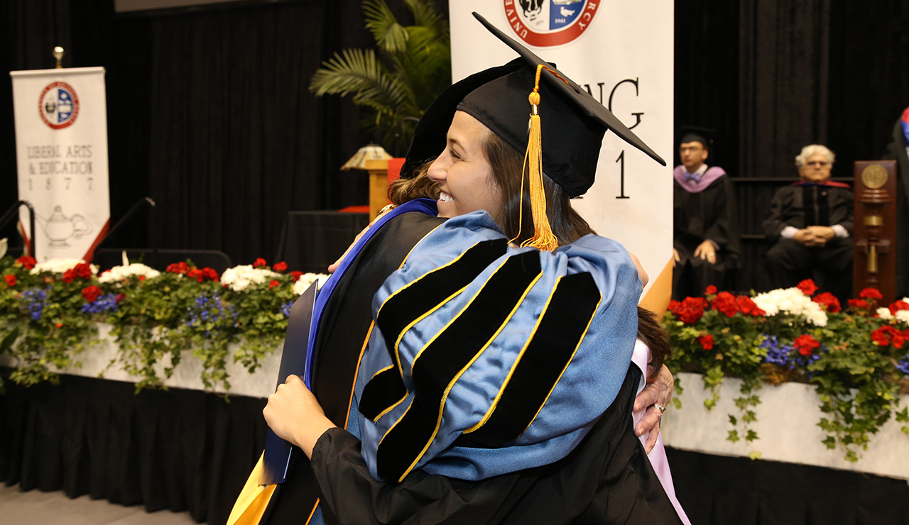 Student hugging a faculty member at commencement.