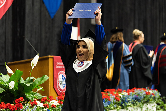 Graduate with diploma cover at commencement