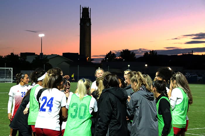 backs of the women's soccer team huddled