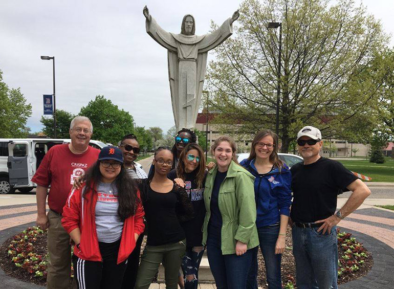 Roy Finkenbine in a group photo under statue on UDM campus
