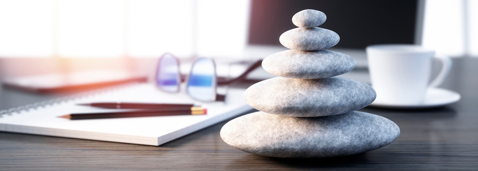 A small tower of stacked smooth stones by a notebook and glasses