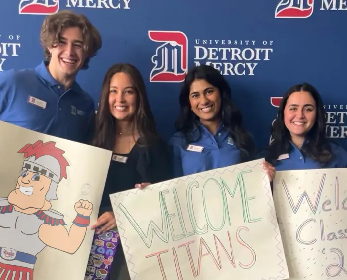 Smiling orientation leaders welcome new students with signs