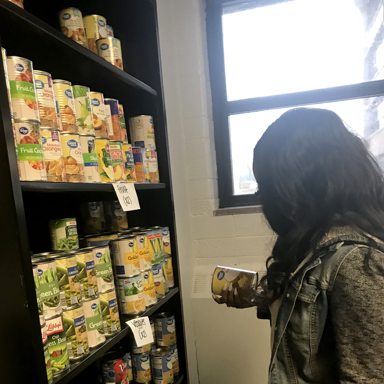 An anonymous Detroit Mercy student selects canned goods from the shelf.