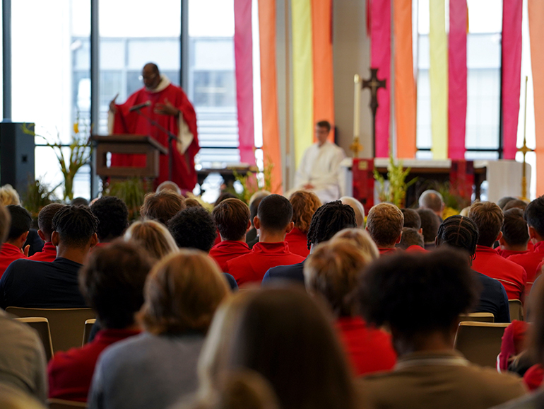 Students listen to a priest presiding during Celebrate Spirit inside of the Student Fitness Center in 2022.