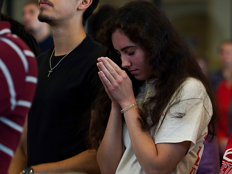 A student prays standing indoors during Celebrate Spirit in 2022.