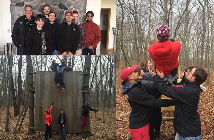 Men climbing a wall, gathering, on retreat