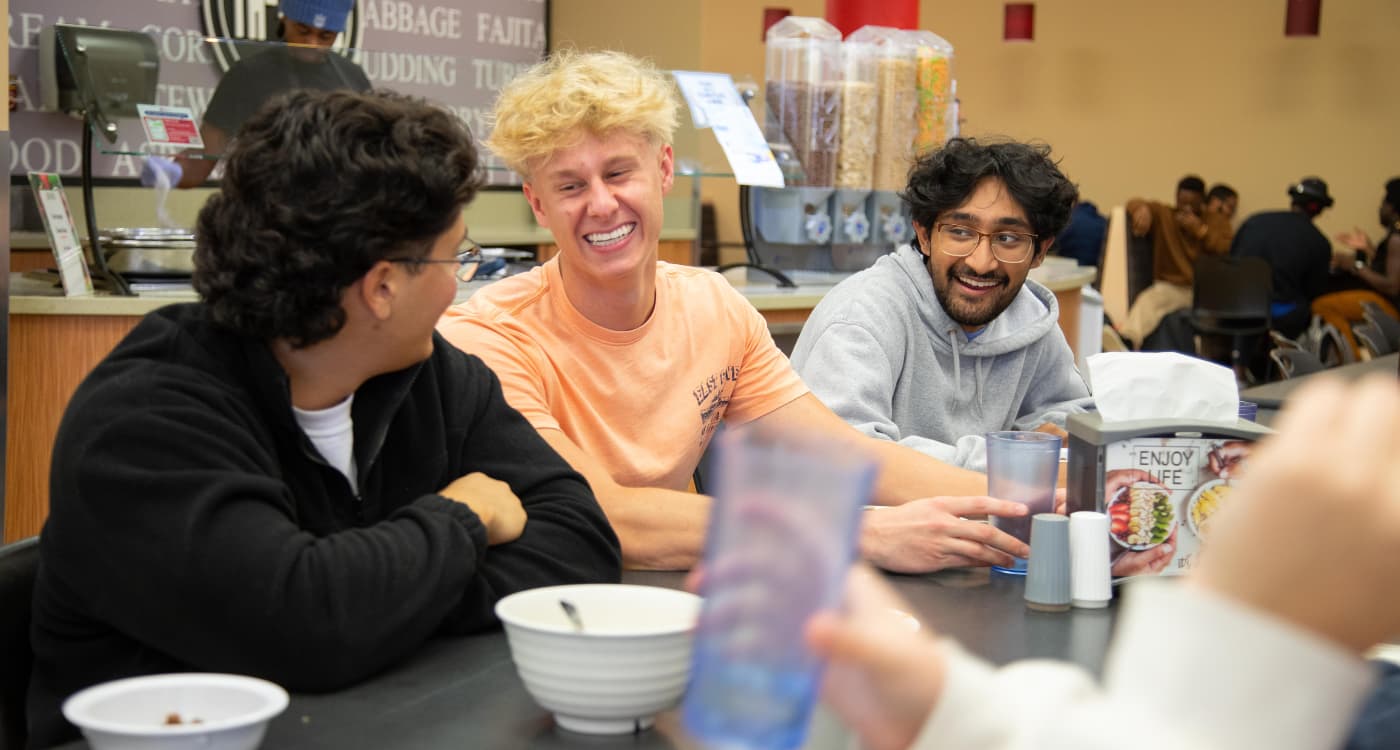 Three students laugh during lunch in the Titan Dining Room.