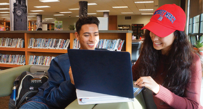 Two students look at a laptop.